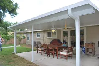 Covered dining patio with tan retractable shades, ceiling fans, and patio heaters under a white ceiling