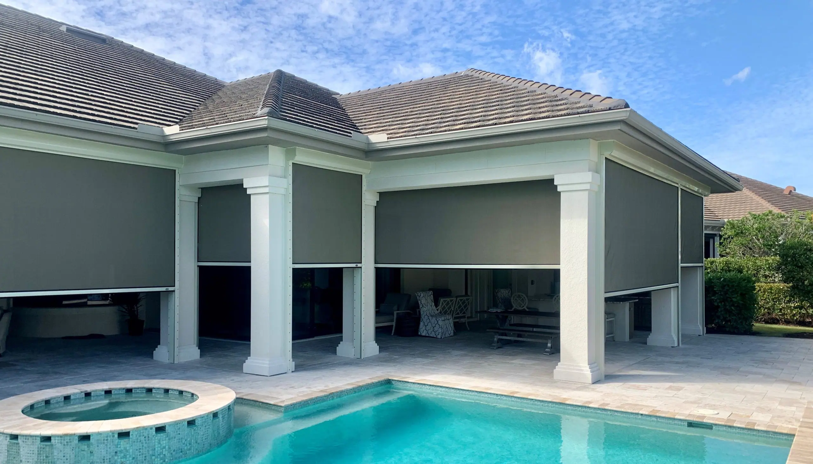 Modern poolside patio with black pergola, two ceiling fans, privacy slats, and outdoor kitchen area